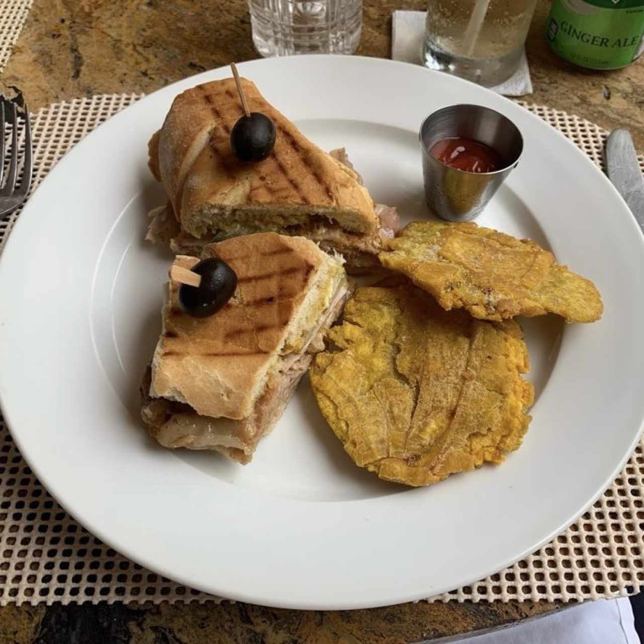 Sandwich Cubano: Pernil, Jamón, queso suizo y pepinillo con tostones de plátano, pan francés