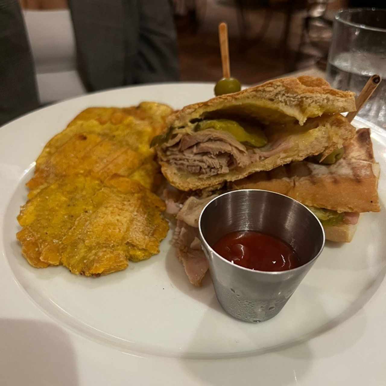 Sandwich Cubano: Pernil, Jamón, queso suizo y pepinillo con tostones de plátano, pan francés