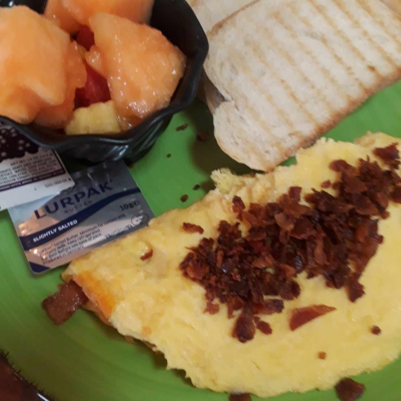 Desayuno con omelet y beicon, frutas y capuchino