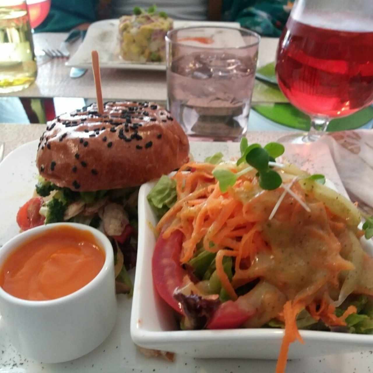 hamburguesa vegetariana, ensalada primavera, té frio orgánico y tartar de atún al fondo