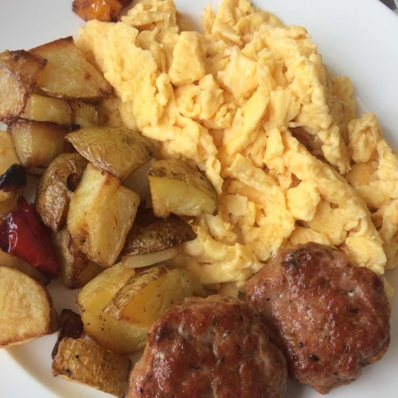 Huevos al gusto servidos con papas asadas al romero y salchichas