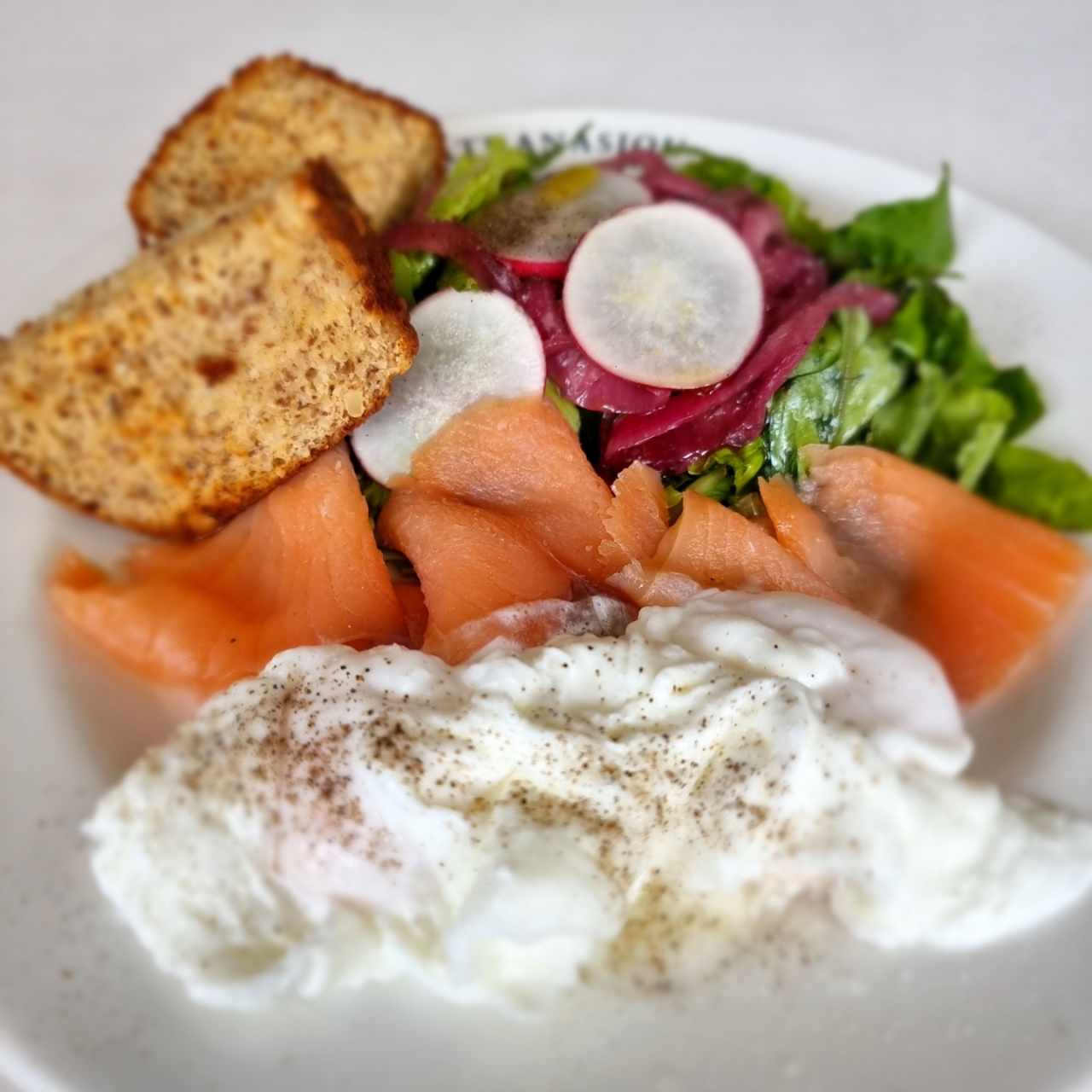 huevos pochados con salmón, ensalada y pan.