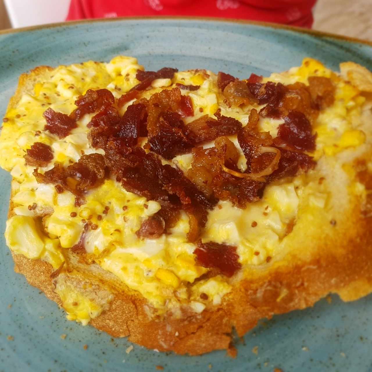 Huevos revueltos con bacon y mostaza dijon sobre tostada de pan