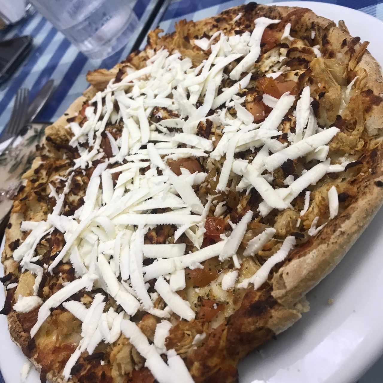 Pizza de pollo con tomate en trocitos y queso feta al entrar y al salir