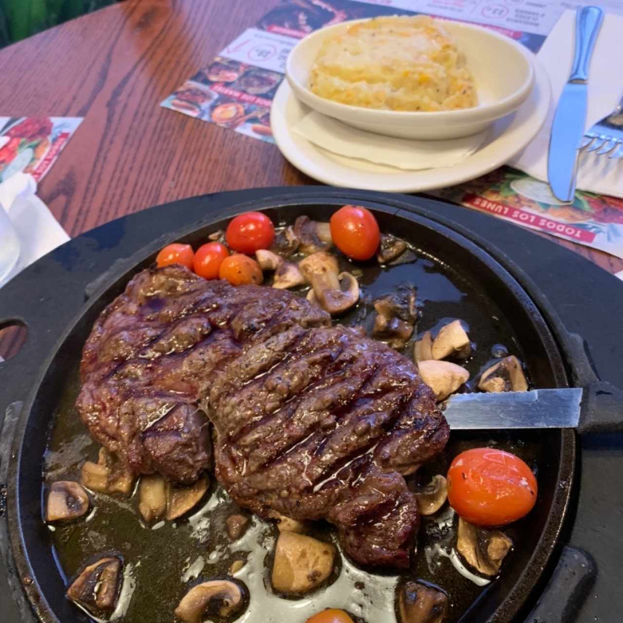 Ribeye con hongos y tomates cheery acompañado de pure con maiz