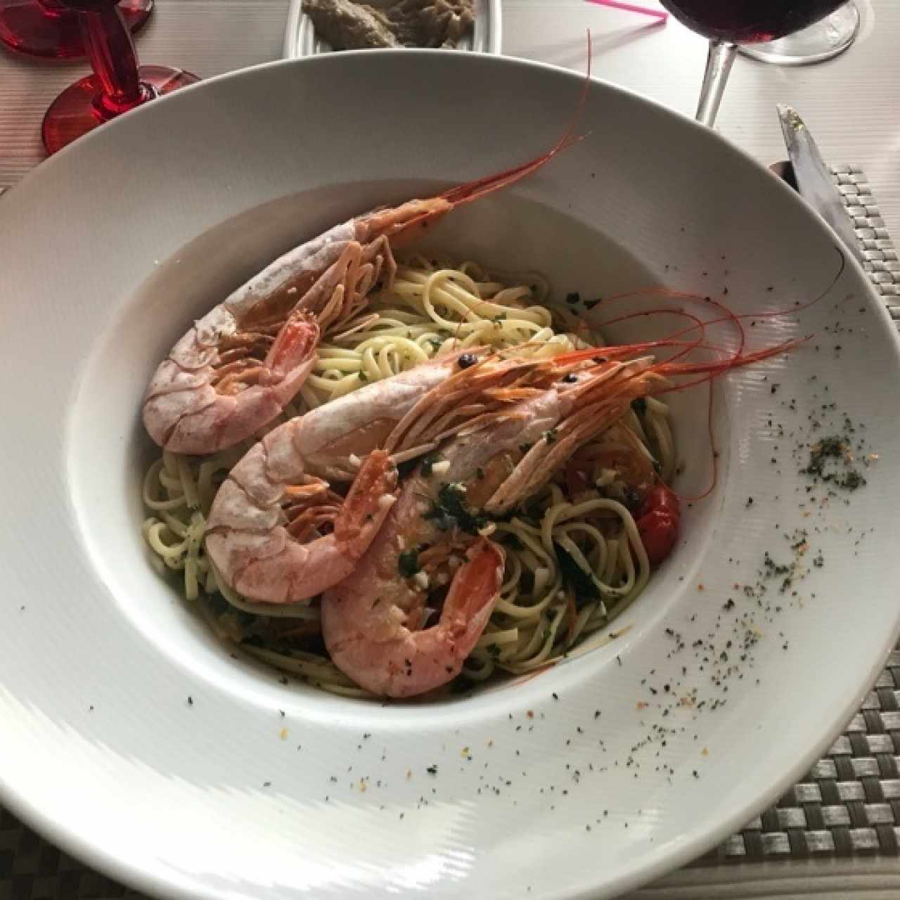 Pasta al olio con tomates cherry y espárragos acompañados de langostinos.