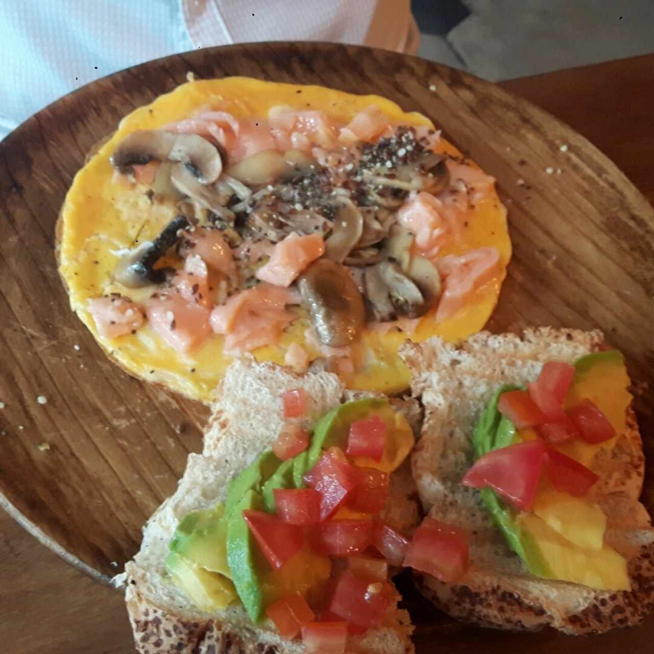 Huevos con salmón y hongos acompañados de tostada de aguacate y tomate