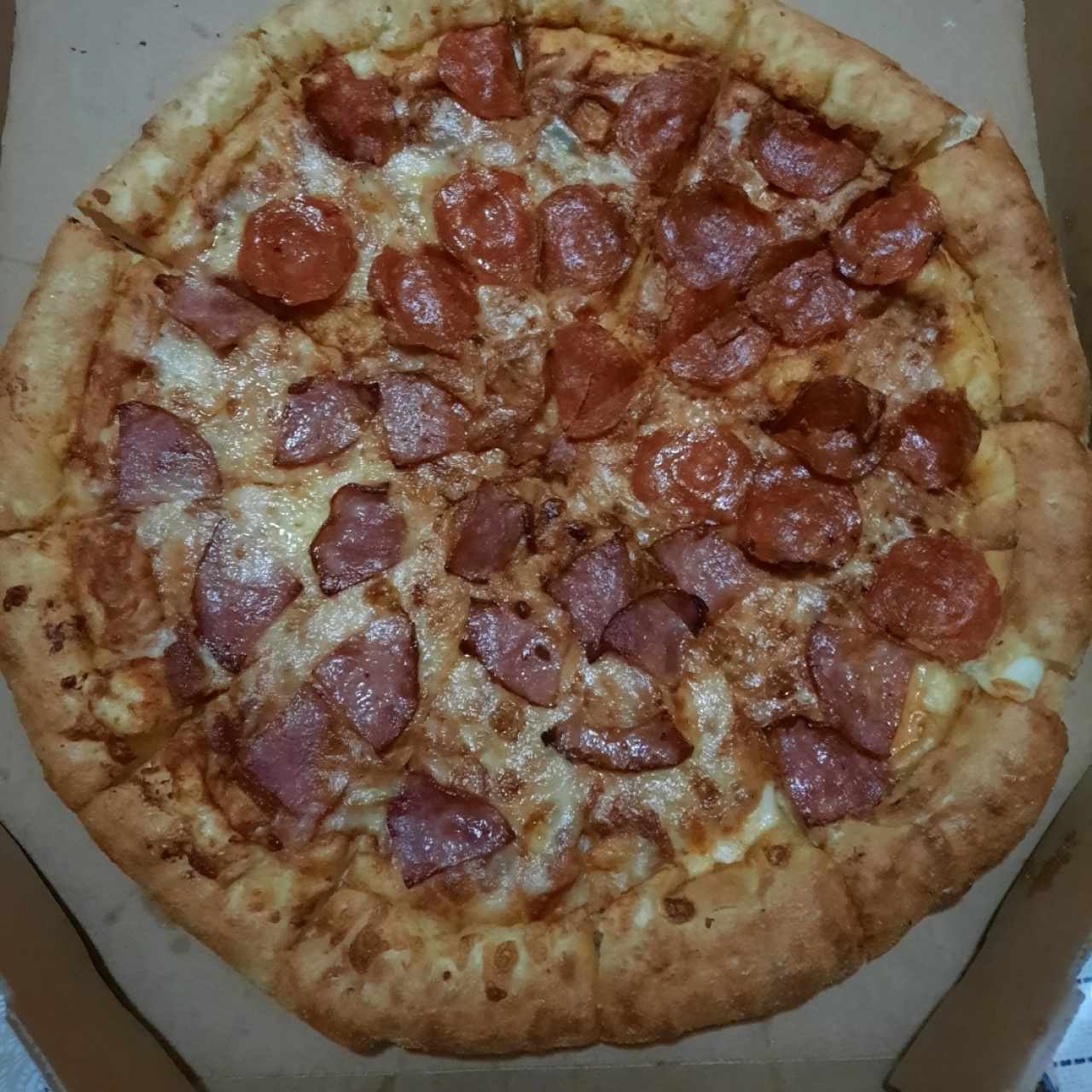 pizza mitad pepperoni mitad jamón con queso en los bordes 