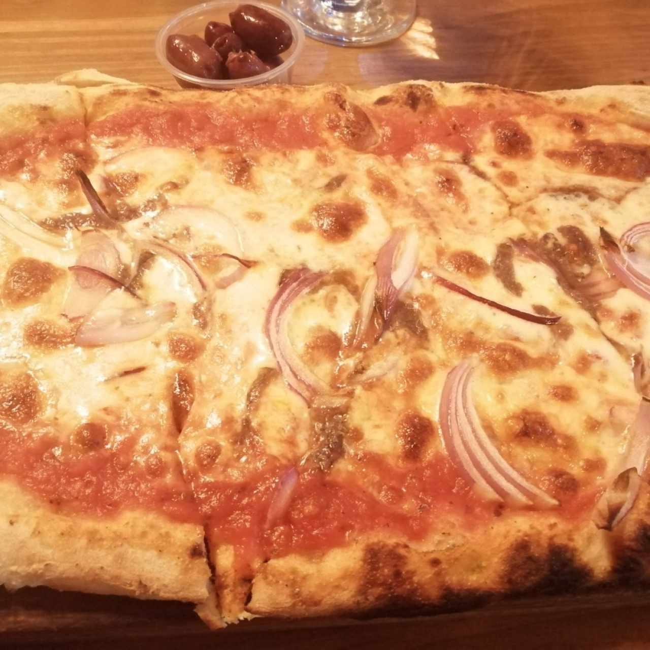 Pizza con anchoas, cebilla morada, kalamatas y cebolla caramelizada. 