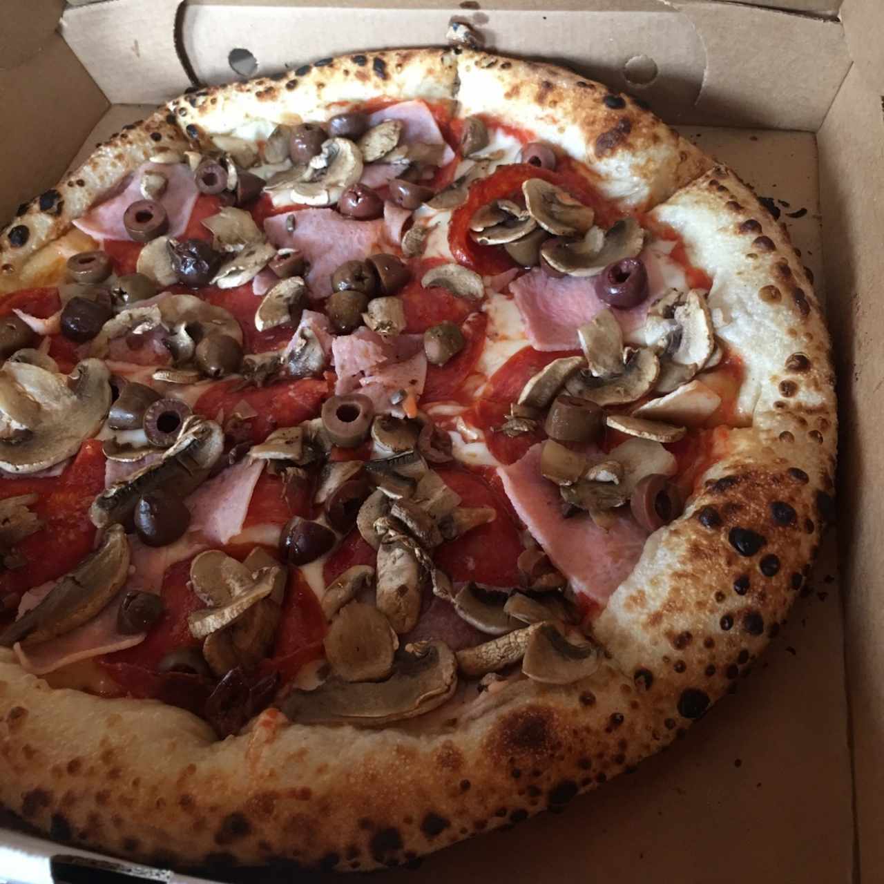 pizza , con aceitunas negras , jamon y peperoni 