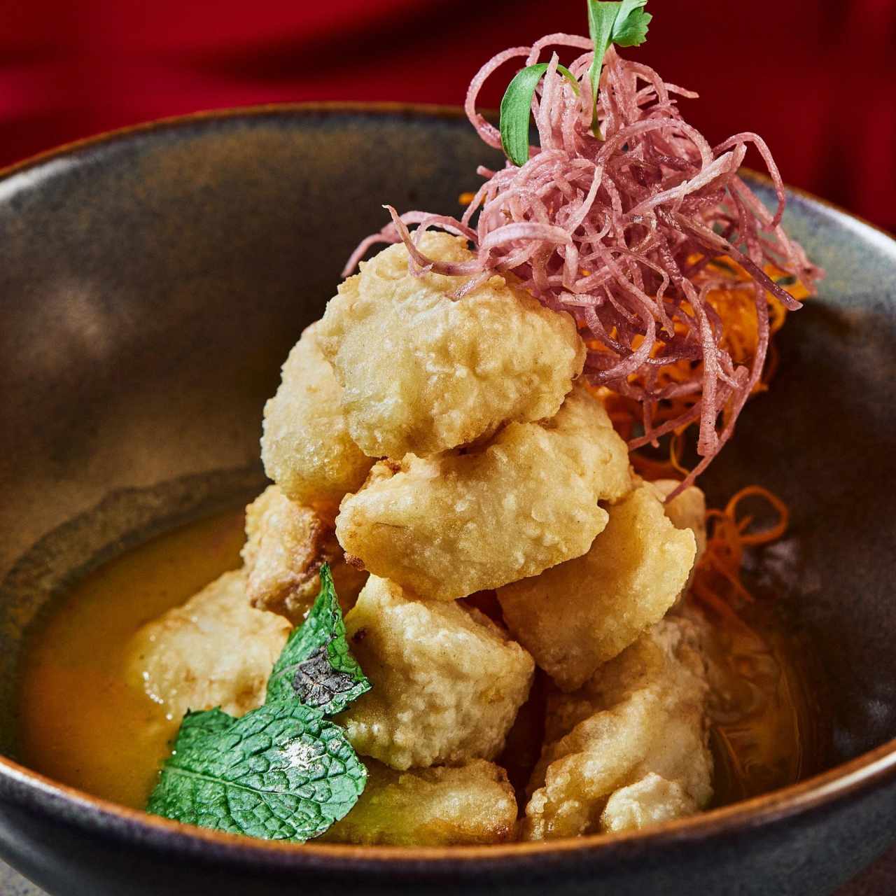 Ceviche de pescado frito en reducción de leche de coco, jengibre y maracuyá con un toque de hierba buena