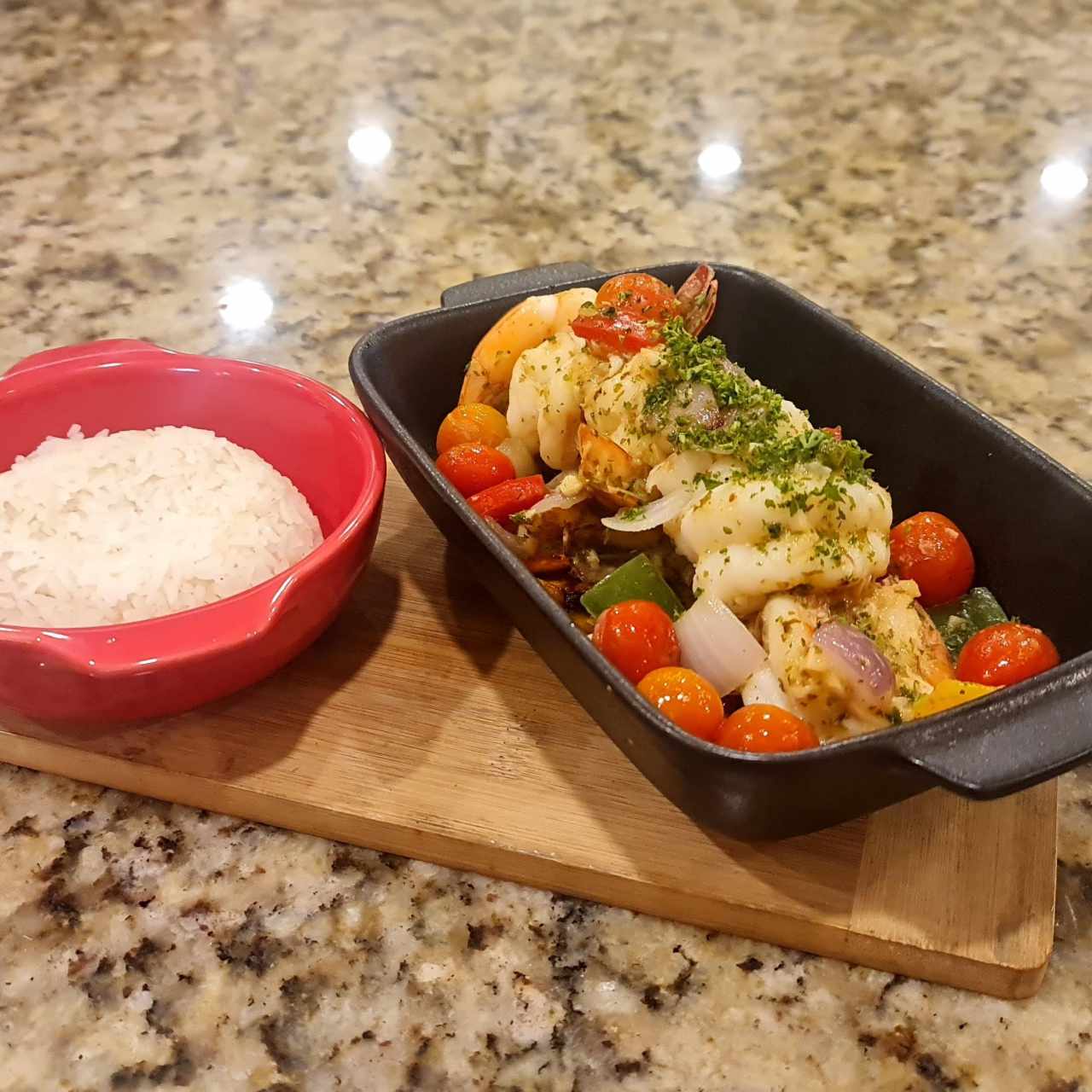 Langostinos salteados con vegetales frescos al vino en salsa al ajillo casera con tomate cherry y cama de plátano maduro y arroz blanco de acompañamiento