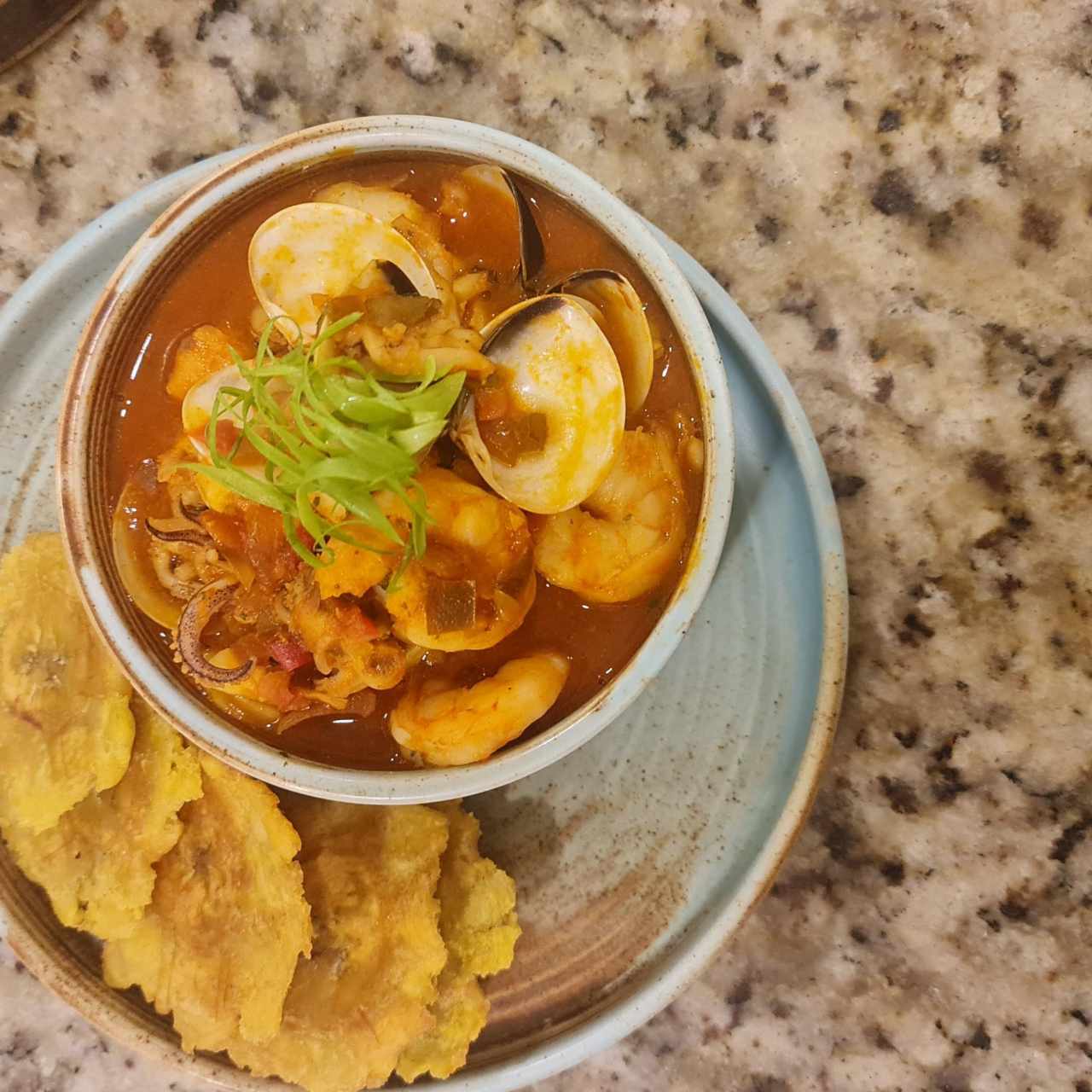 Estofado de mariscos salteados con vegetales frescos en salsa criolla, acompañado de crujientes patacones