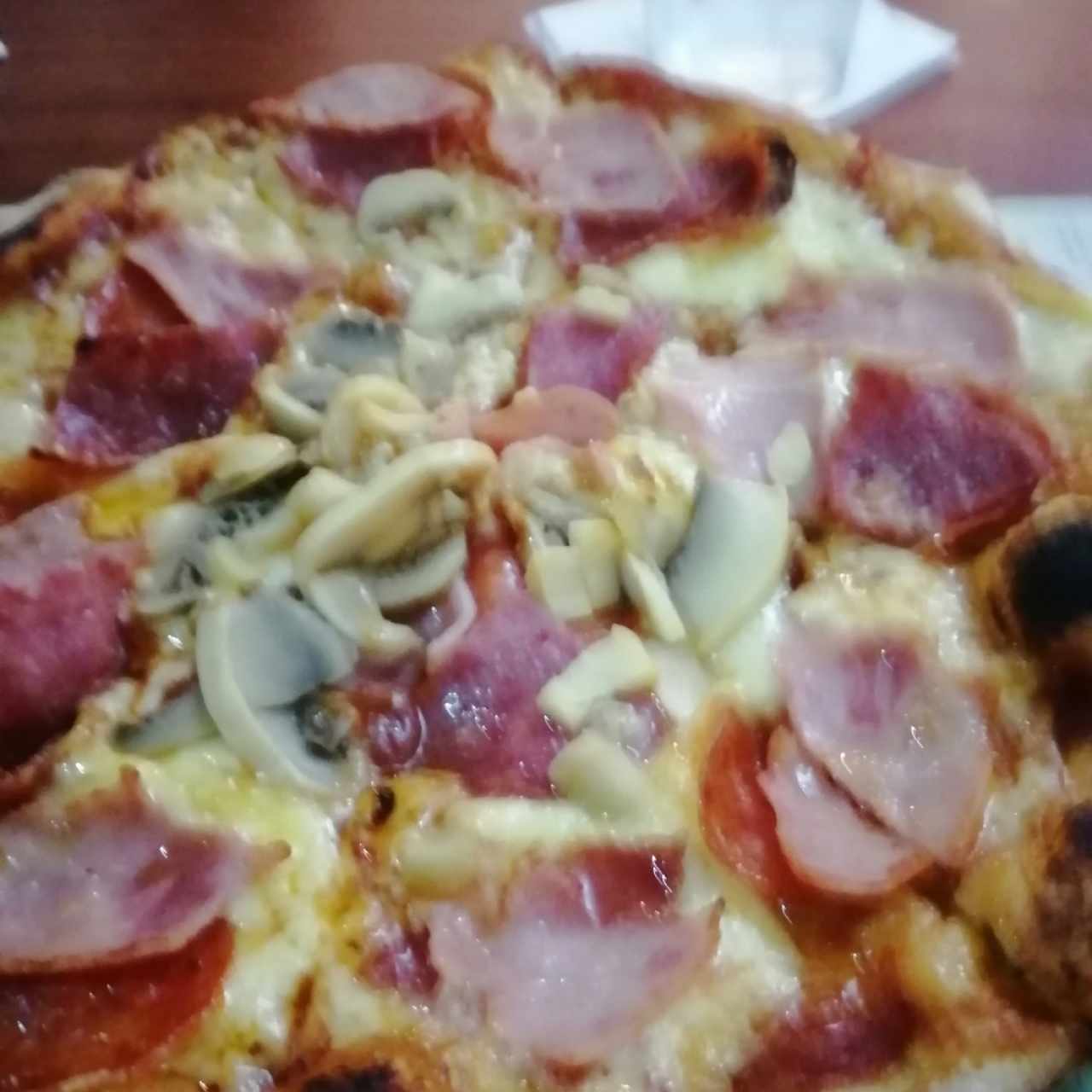 Pizza con jamón, peperoni y hongos