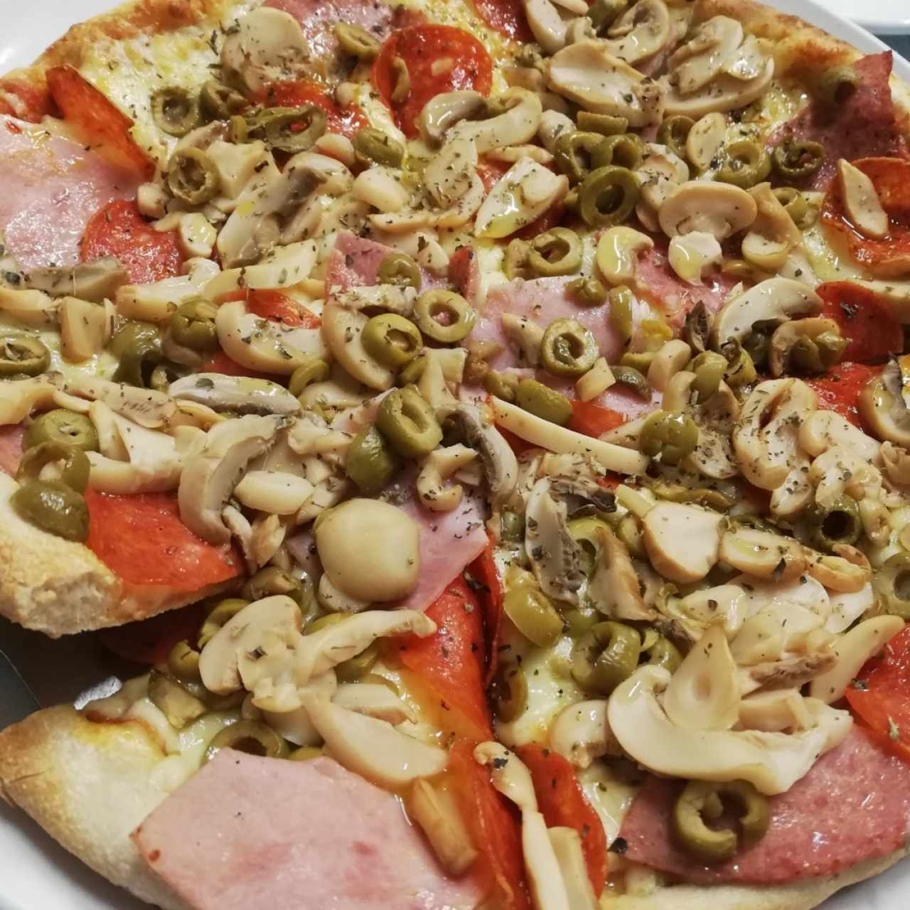 Pizza de jamón, peperoni, hongos y aceitunas
