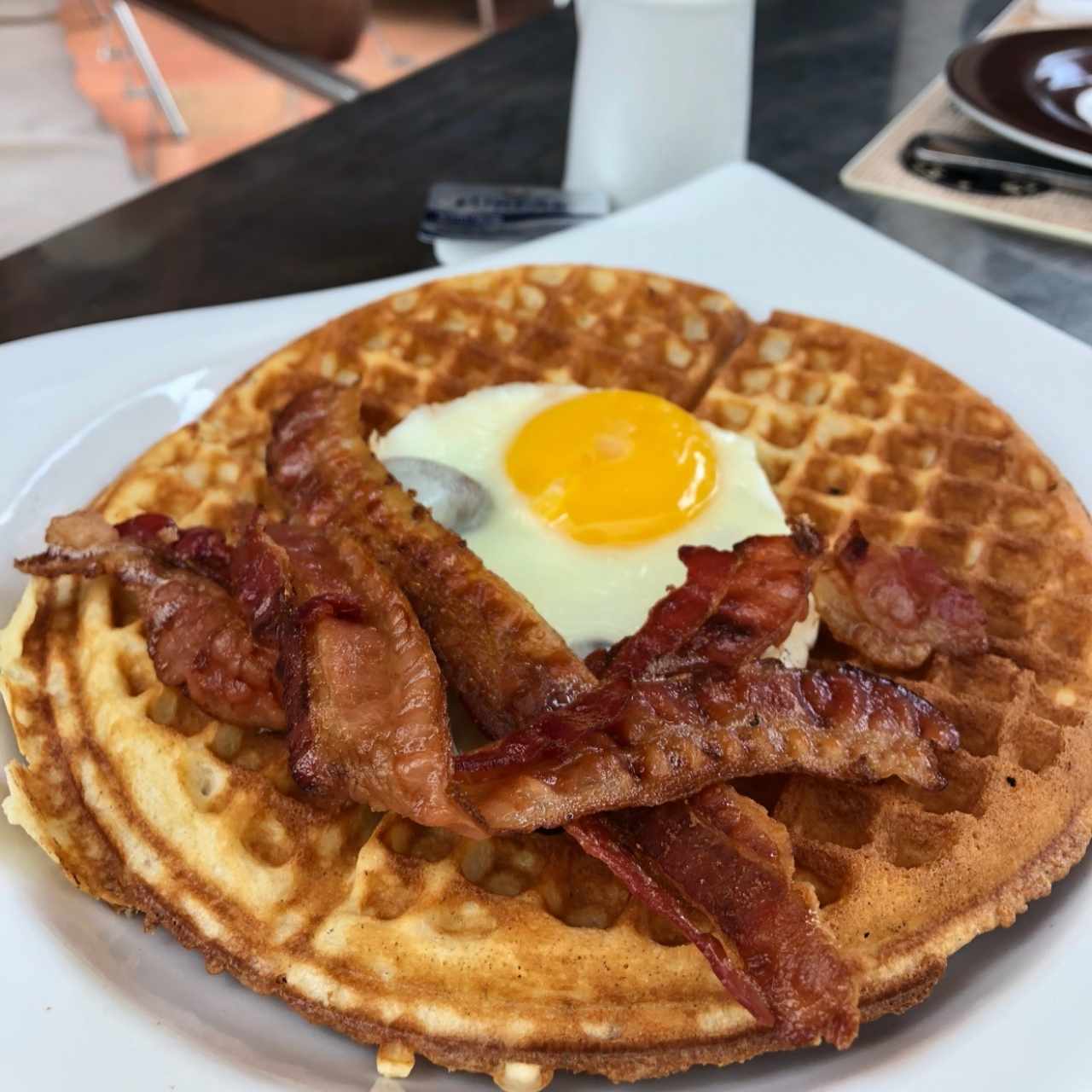 Waffle con huevo, tocineta y syrup del menú brunch