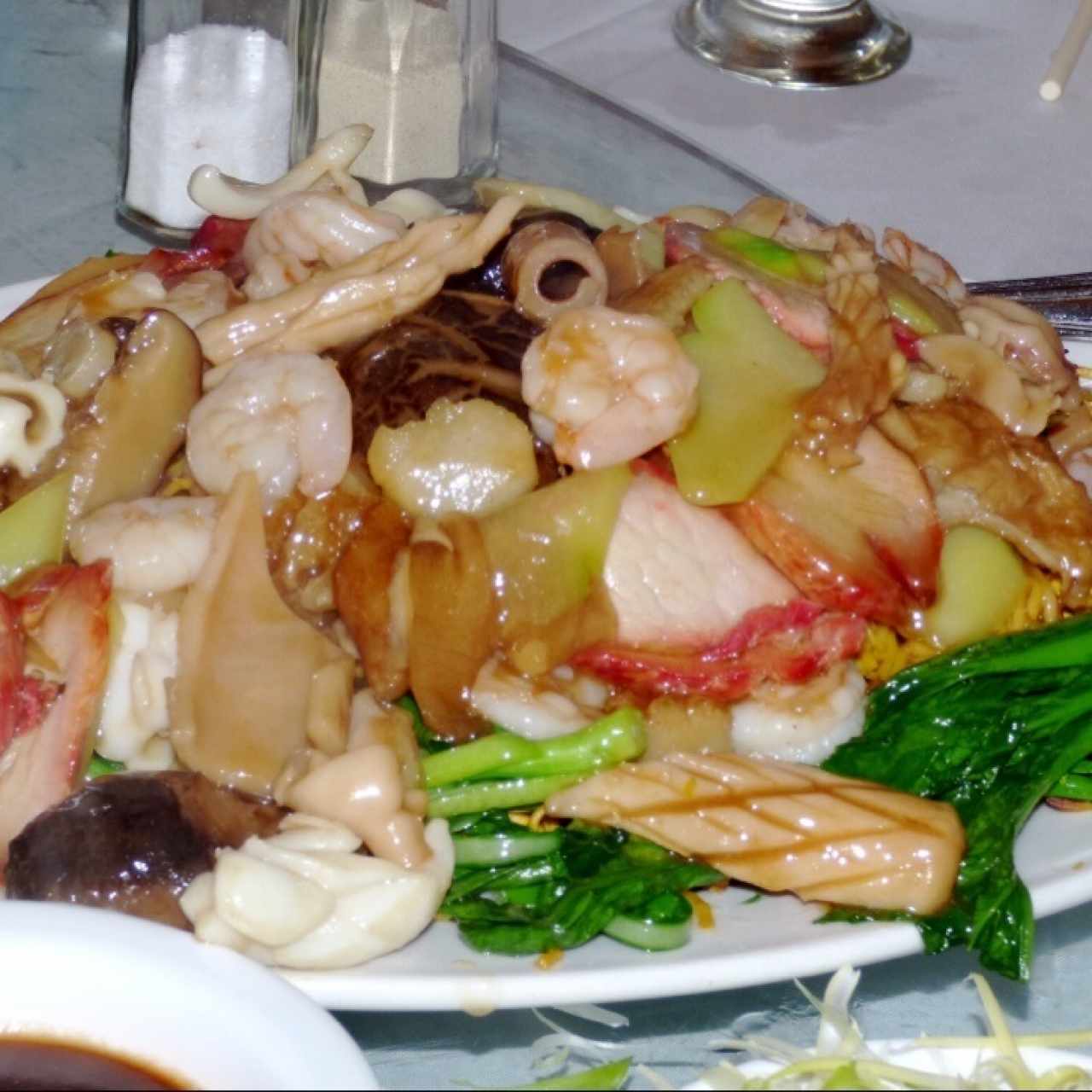Cazuela de mariscos con hojas de mostaza y trozos de puerco asado