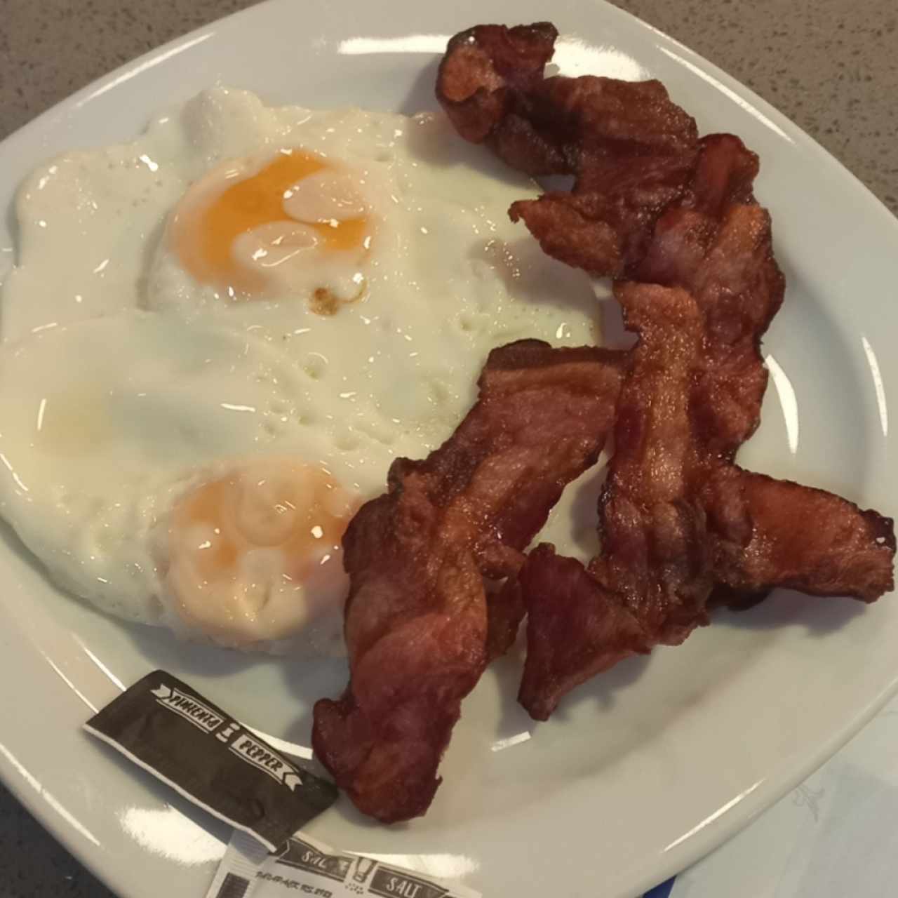 Par de huevos fritos con tocino