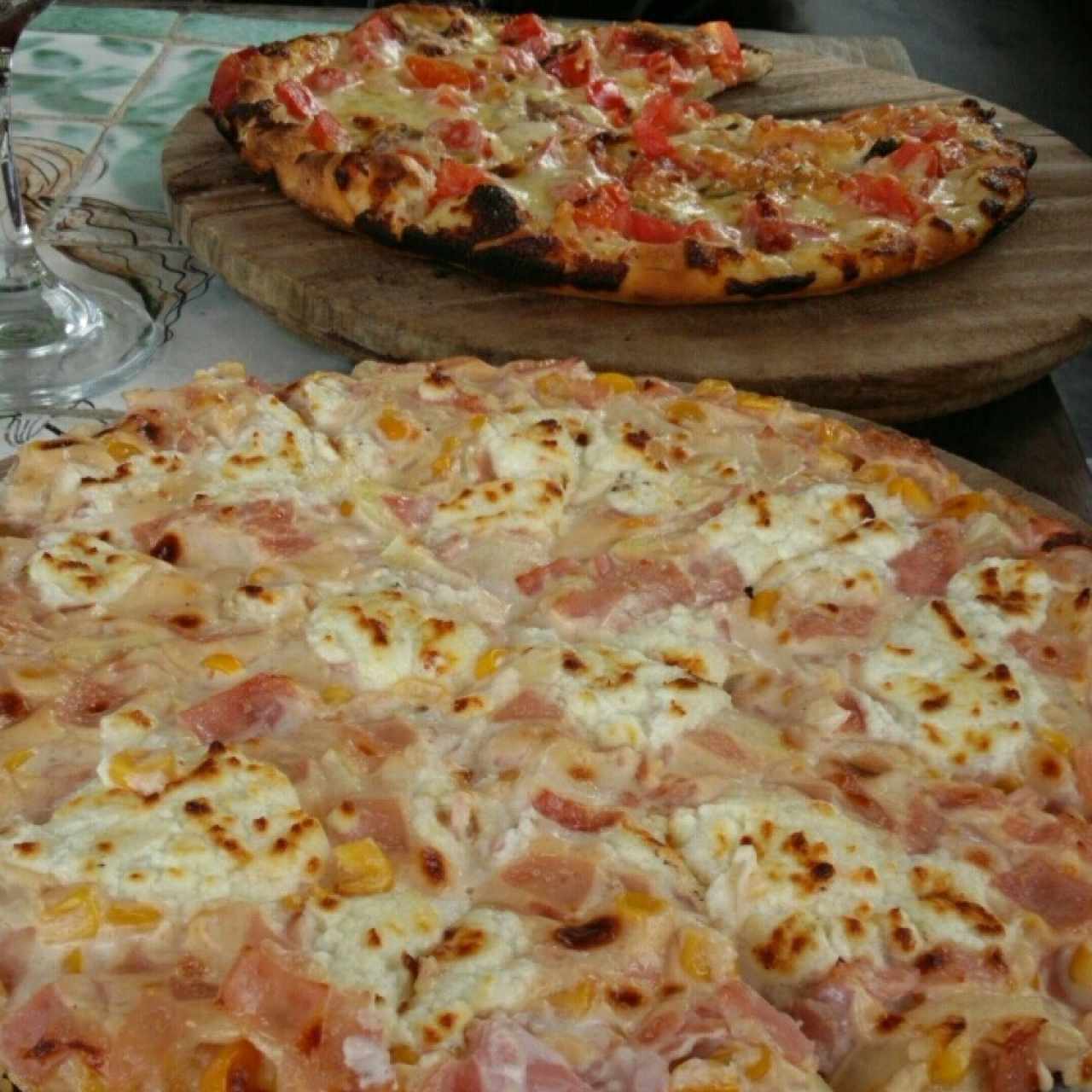 Pizza a la crema  (queso de cabra con tocineta y maiz) y pizza con anchoas