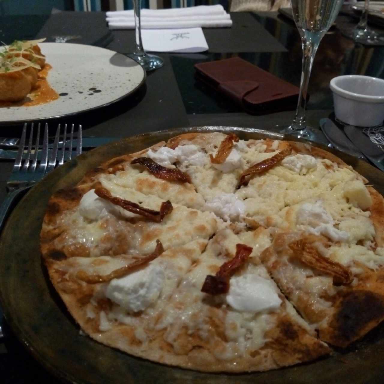 Pizzeta con queso de cabra y tomates secos.  Al fondo Arancinis